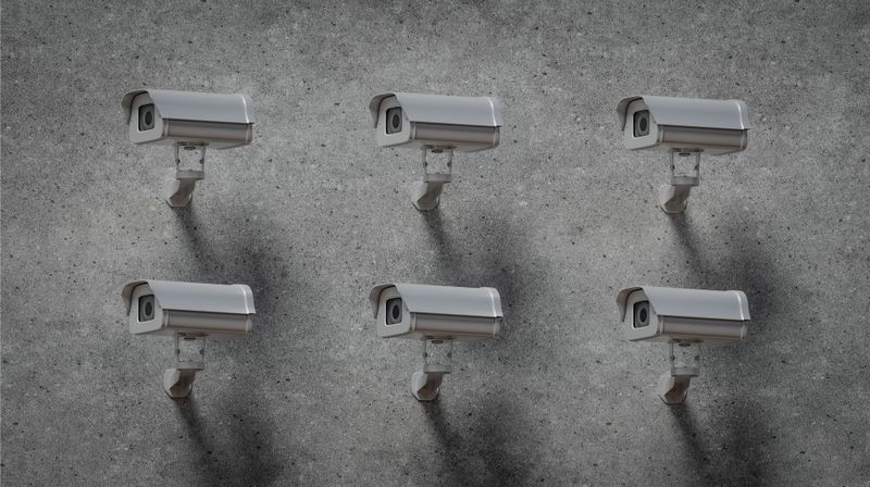 Seis cámaras de vigilancia montadas en una pared de hormigón gris, espaciadas uniformemente en dos filas.