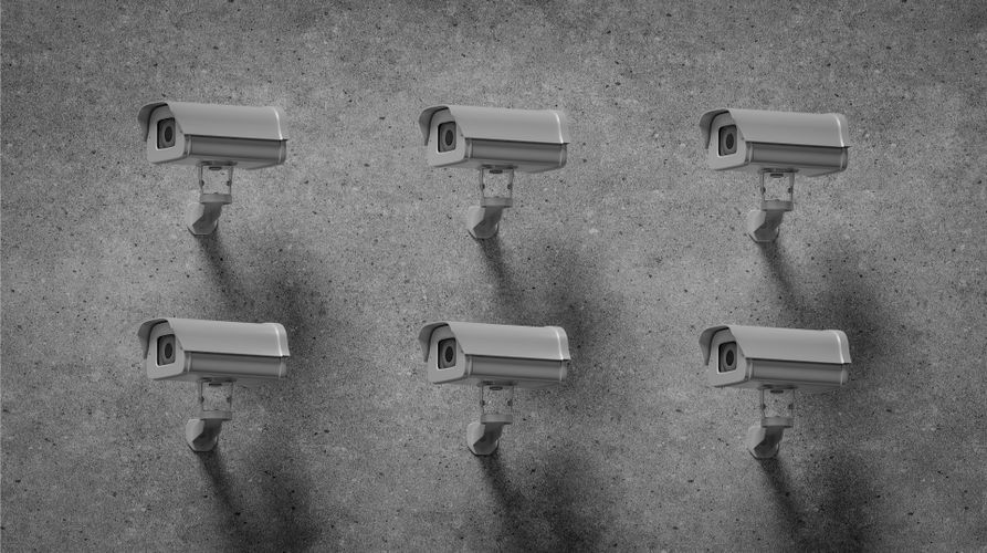 Six surveillance cameras mounted on a gray concrete wall, evenly spaced in two rows, casting shadows below.