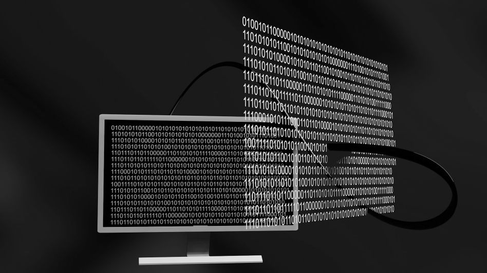 A computer monitor with binary code flowing out of the screen, creating a digital stream effect against a dark background.