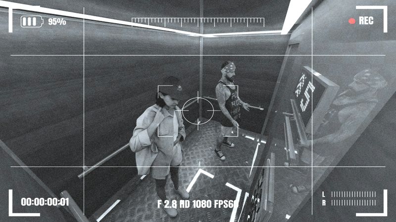 Surveillance footage of two people inside an elevator, both facing the control panel. The image has a grainy, monochrome effect.