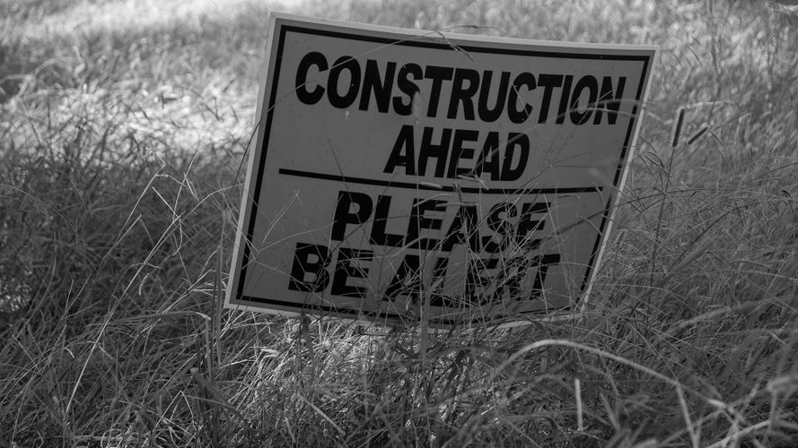 zdjęcie czarno-białe tablicy z napisem „Construction ahead please be alert”