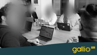 Eine Gruppe von Leuten sitzt um einen Tisch und benutzt Laptops in einem Büro.