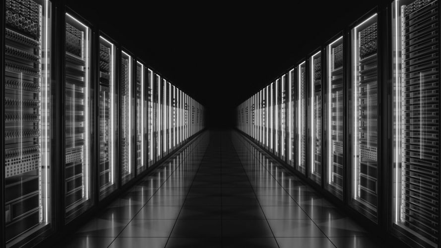 Ein schwach beleuchtetes Rechenzentrum mit Reihen von beleuchteten Server-Racks auf beiden Seiten und einem reflektierenden Boden, der in die Dunkelheit führt.