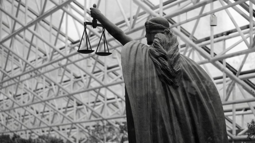 czarno-białe zdjęcie dużej rzeźby kobiety trzymającej w lewej ręce wagę symbol sprawiedliwości