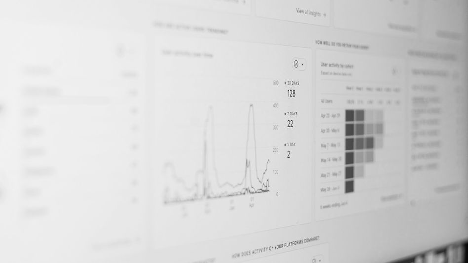 A grayscale image of a computer screen displaying analytics with graphs and data charts.