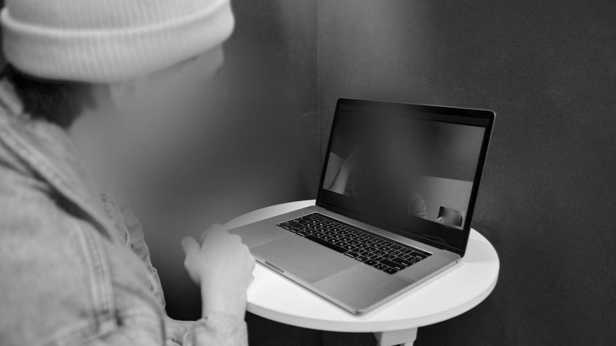 czarno-białe zdjęcie z mężczyzną obok laptop z wideo rozmową twarze zblurowane