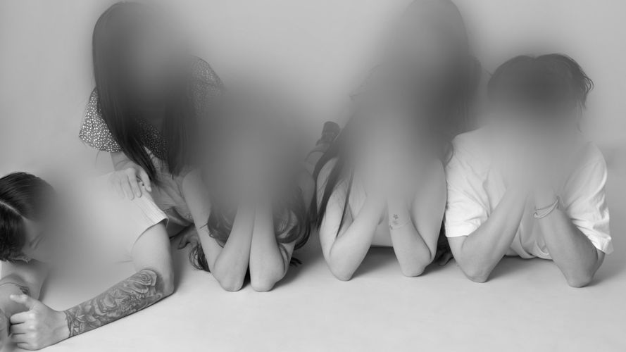 Rozmyte, zanonimizowane twarze nastolatków leżących na ziemi, zdjęcie czarno-białe