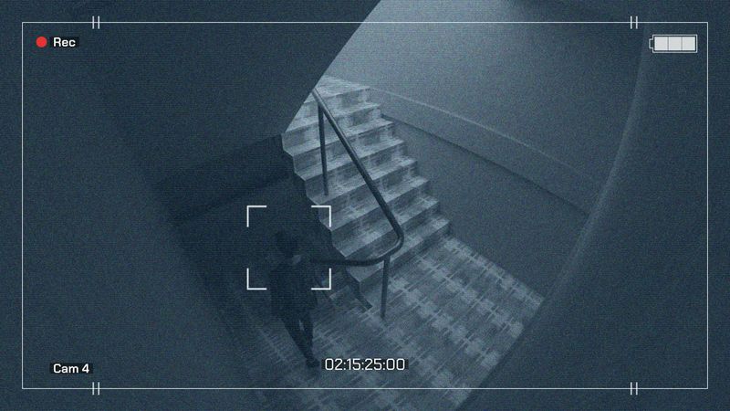 Überwachungskameramaterial, das eine Person zeigt, die eine Treppe in einem schwach beleuchteten Bereich hinaufgeht. Zeitstempel und Kameradetails sind sichtbar.