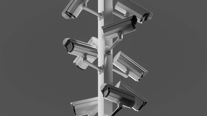 Multiple surveillance cameras mounted on a tall pole against a gray background, arranged in a spiral pattern.