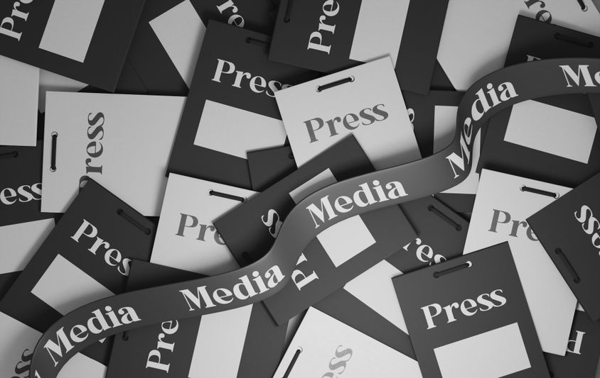 Une pile de badges de presse en noir et blanc avec les mots « Presse » et « Médias » imprimés dessus, disposés de manière dispersée.