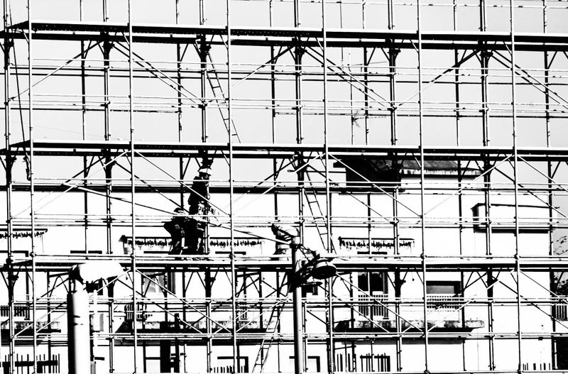 Fotografía en blanco y negro de un andamio con un edificio al fondo.