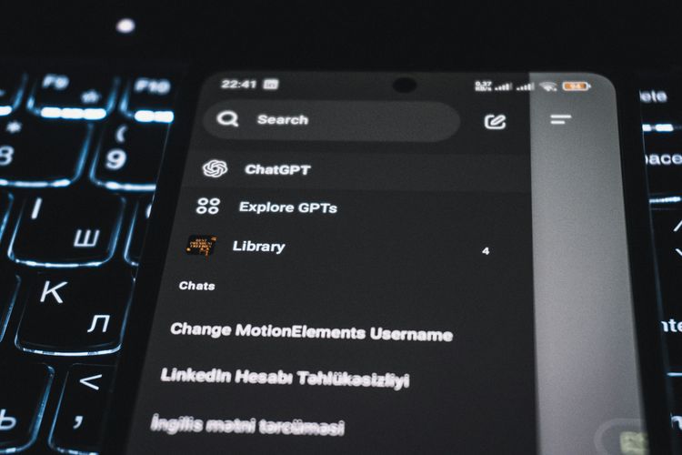 zdjęcie telefonu z chatem gpt i laptopa z podświetloną klawiaturą