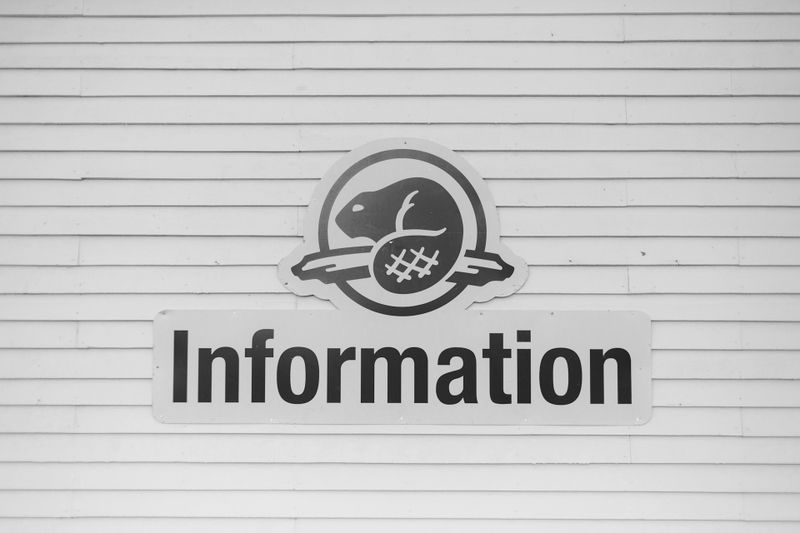 Panneau noir et blanc avec un logo de castor au-dessus du mot « Information » sur un mur ligné.