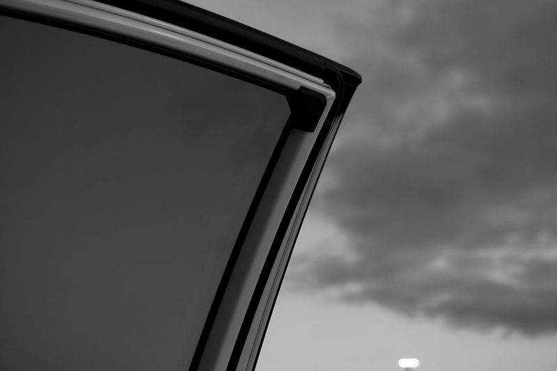 foto en blanco y negro de la puerta de un coche con las ventanas polarizadas, en el fondo el cielo