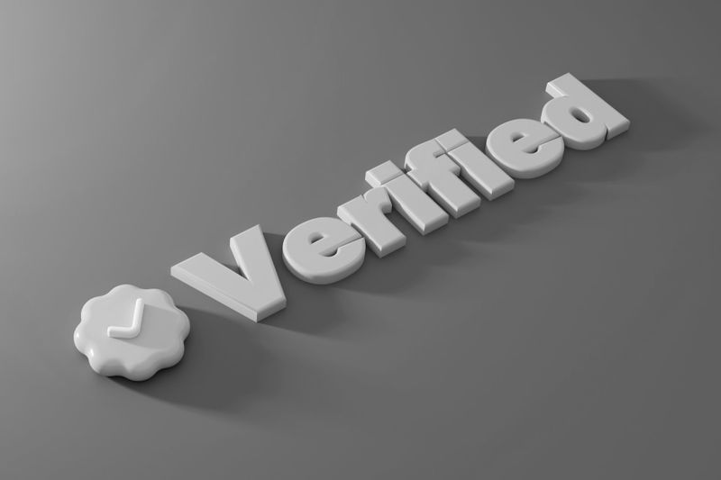 Texte 3D « Vérifié » avec une coche à l'intérieur d'un badge sur fond gris.
