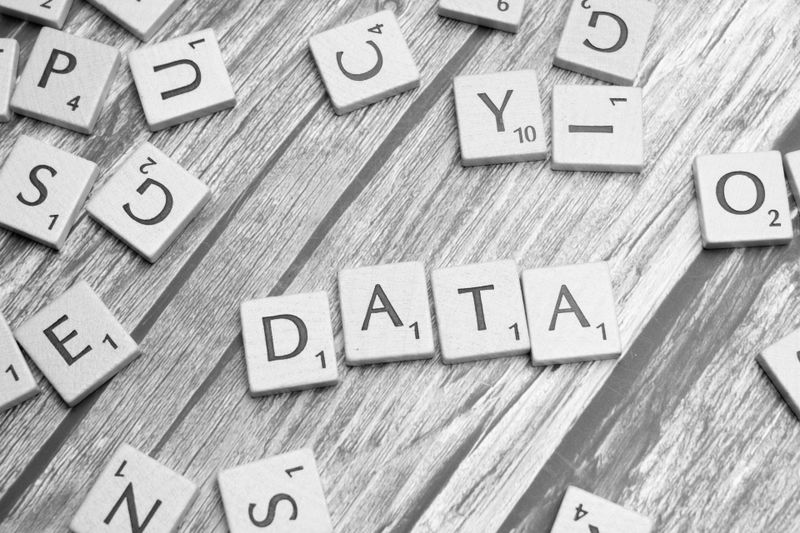 Tuiles de Scrabble épelant « DATA » sur une surface en bois, entourées de lettres dispersées.