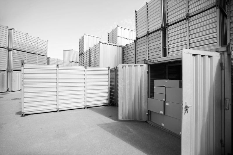Personne plaçant une boîte dans un box de stockage en hauteur à l’aide d’une échelle mobile.