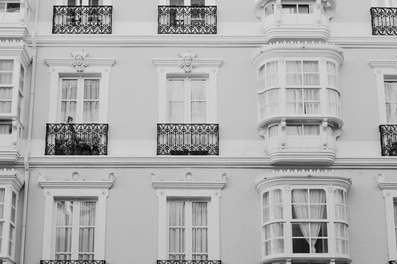 Maison de ville blanche avec enduit au-dessus des fenêtres, photo en noir et blanc.