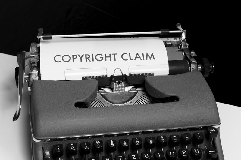 Une machine à écrire vintage avec une feuille de papier affichant le texte « COPYRIGHT CLAIM » en lettres grasses.