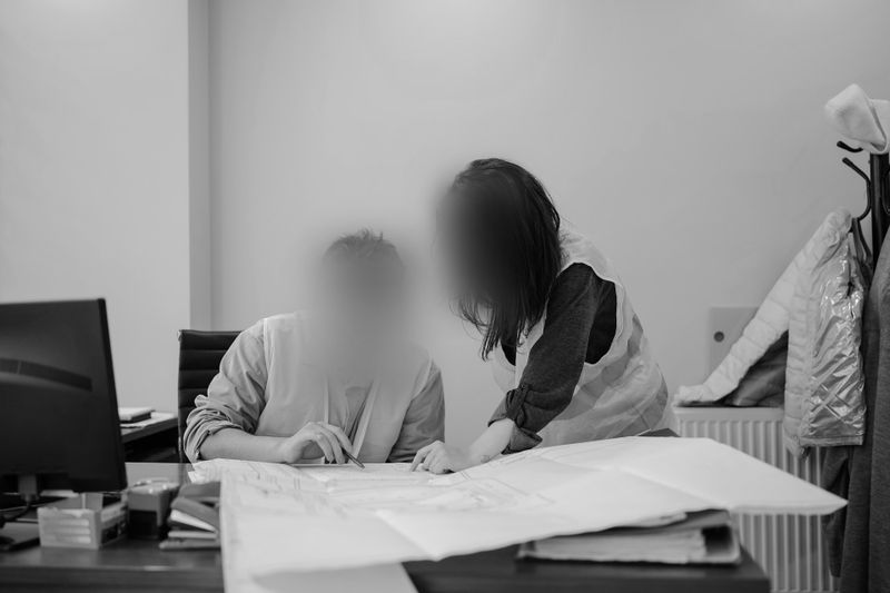 Fotografía en blanco y negro de empleados de oficina junto a un escritorio lleno de papeles.