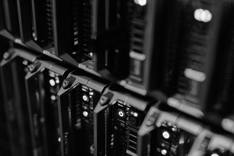 Nahaufnahme einer Reihe schwarzer Server-Racks in einem Rechenzentrum, mit gedämpfter Beleuchtung, die die Metallkomponenten hervorhebt.