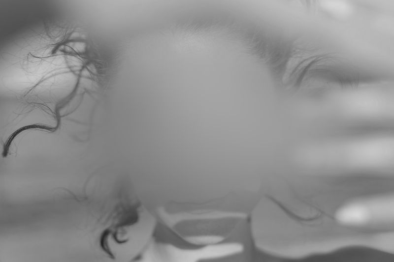 Abstract black and white image of a person with blurred face, surrounded by flowing hair and hands, creating a mysterious and artistic effect.