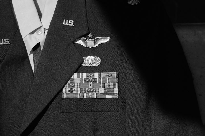 Close-up of a military uniform showing U.S. insignia, pilot wings, and multiple service ribbons, in black and white.