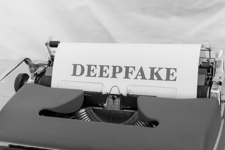 Maszyna do pisania z kartką papieru, na której widnieje słowo „DEEPFAKE” napisane pogrubionymi, wielkimi literami.