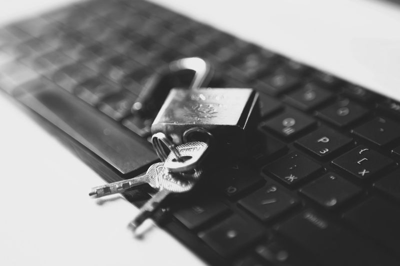 Cadenas et clés reposant sur un clavier noir, symbolisant la cybersécurité. Image en noir et blanc.