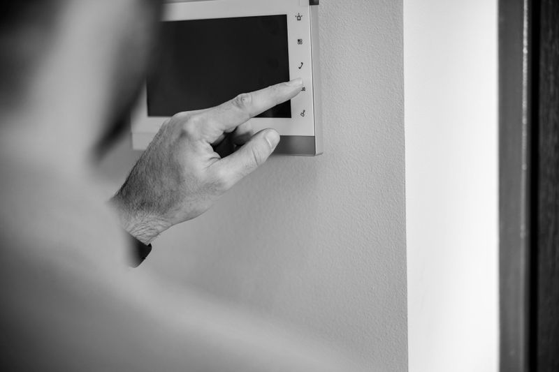 Osoba naciskająca przycisk na ekranie lub panelu sterowania zamontowanym na ścianie.