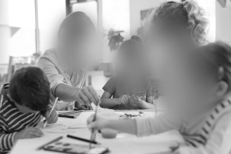 Groupe de personnes participant à une activité créative autour d’une table, avec du matériel artistique tel que des pinceaux et du papier, dans une pièce bien éclairée.