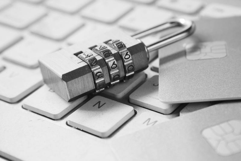 Cadenas sur un clavier avec des cartes de paiement, symbolisant la sécurité et la confidentialité numériques. Image en noir et blanc.