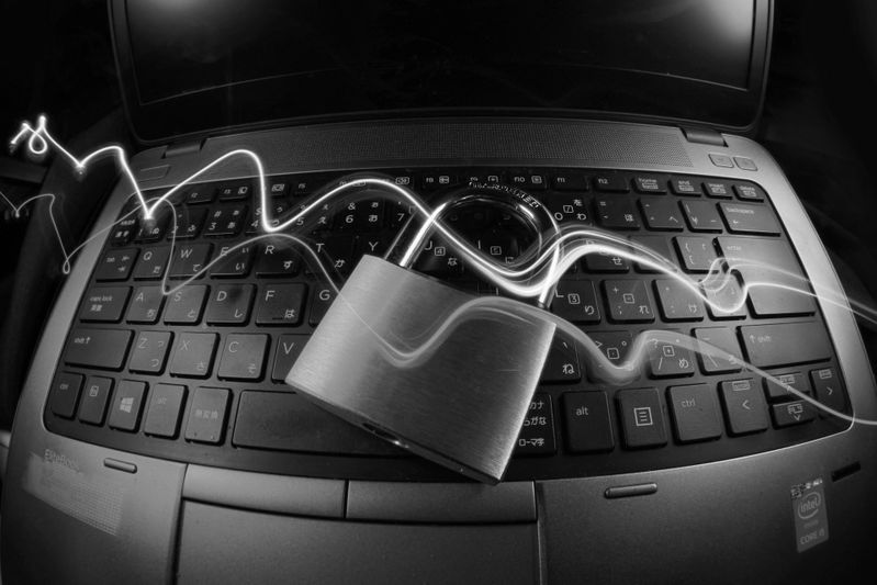 Ein Vorhängeschloss auf einer Laptop-Tastatur mit wirbelnden Lichtspuren, die Cybersicherheit oder Datenschutz symbolisieren.