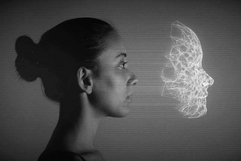Profil d'une femme faisant face à une tête filaire numérique sur fond sombre, symbolisant la technologie et le lien humain.
