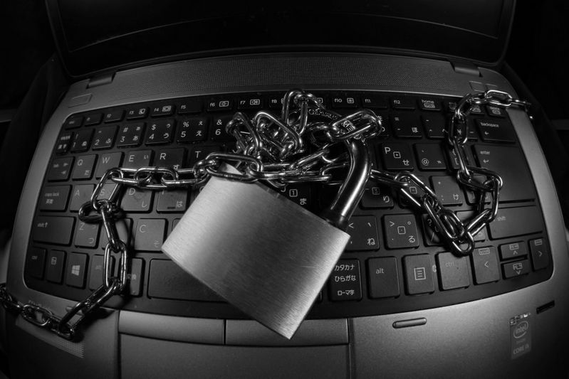 A laptop keyboard with a metal chain and padlock placed on top, symbolizing security or data protection.