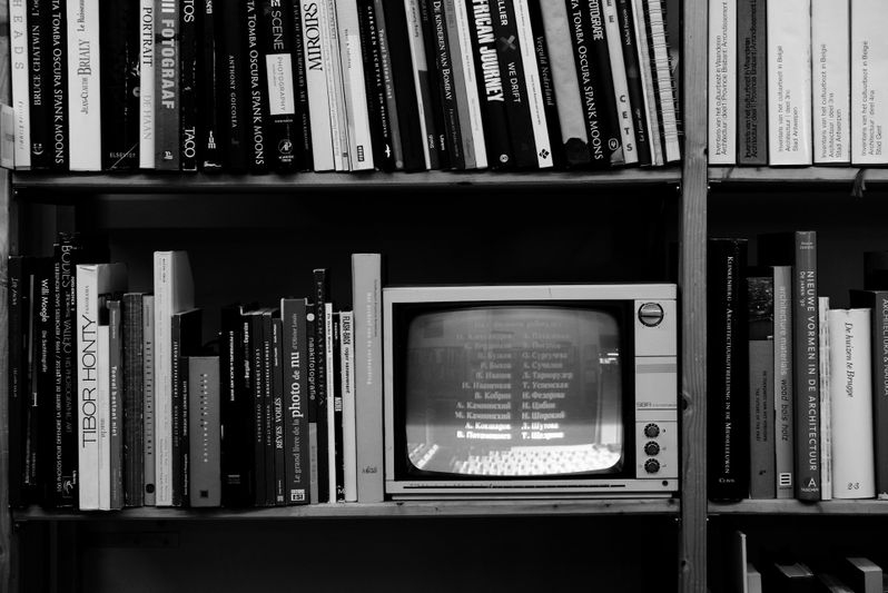black-and-white photo of shelves with books and a small CRT television