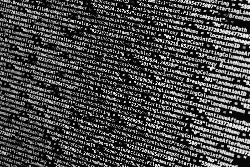 Gros plan d'un écran d'ordinateur affichant des lignes de code en texte blanc sur fond noir, comportant divers termes et symboles de programmation.