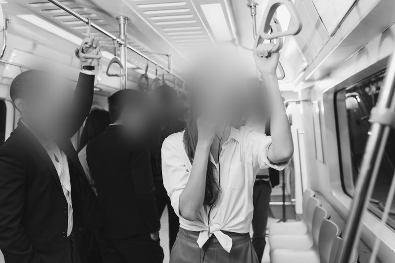 Des passagers debout dans un métro, tenant les poignées au-dessus de leur tête. Le train est bien éclairé et pas bondé.