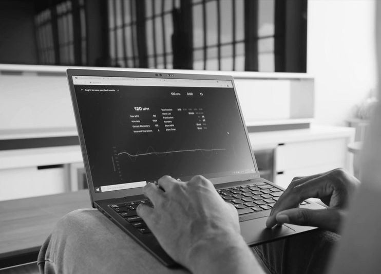 Personne tapant sur un ordinateur portable affichant des analyses et des graphiques sur l'écran dans un cadre monochrome.