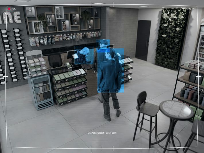 Security camera footage of a store interior showing customers at the counter, with plants and display shelves, timestamped 05/06/2021 2:25 AM.