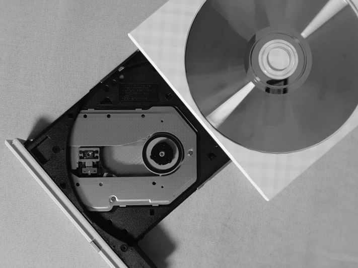 fotografía en blanco y negro de un reproductor de CD con un disco al revés colocado a su lado