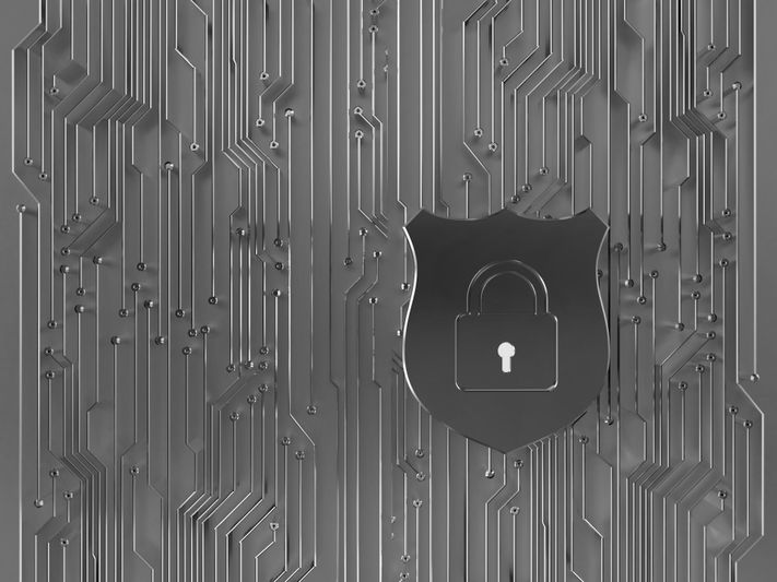 A metallic shield with a padlock icon on a circuit board pattern background, symbolizing cybersecurity and data protection.