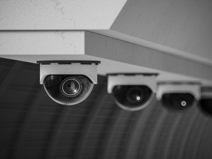 Image en noir et blanc de plusieurs caméras de sécurité dôme montées au plafond, se concentrant sur une caméra au premier plan.