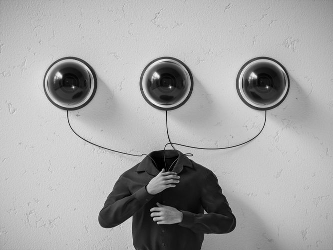 Surrealistyczny obraz bezgłowej osoby, nad którą na ścianie zamontowano trzy duże, okrągłe kamery bezpieczeństwa połączone kablami.