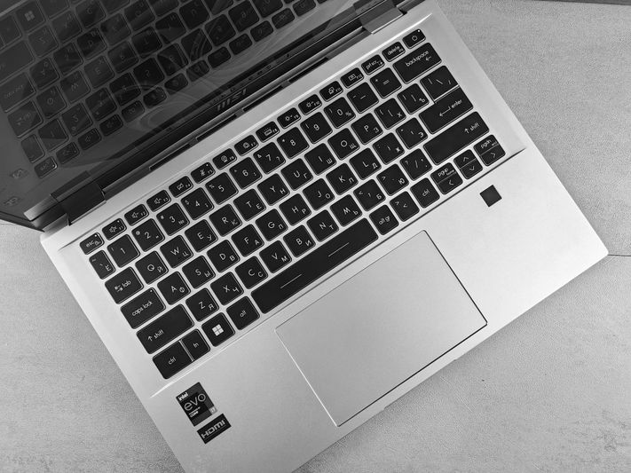 Un ordinateur portable argenté avec un clavier noir doté d'un pavé tactile et d'autocollants Intel Evo et HDMI, placés sur une surface claire.