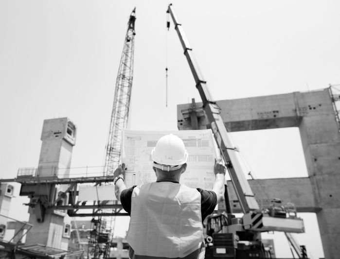 Deux géomètres en gilets réfléchissants travaillent sur un chantier, utilisant des équipements pour mesurer et évaluer des éléments structurels.
