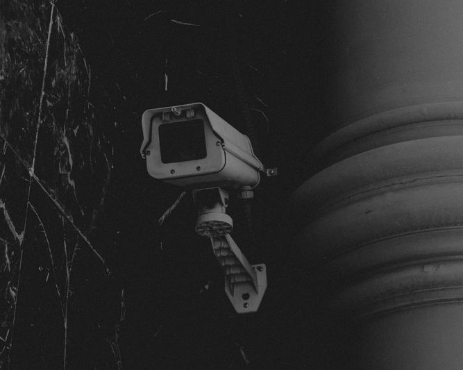 cámara en un poste junto a una pared de piedra negra, foto en blanco y negro