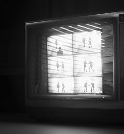 A monochrome TV screen displays six CCTV-like frames of silhouetted figures in different poses, creating a mysterious, vintage effect.