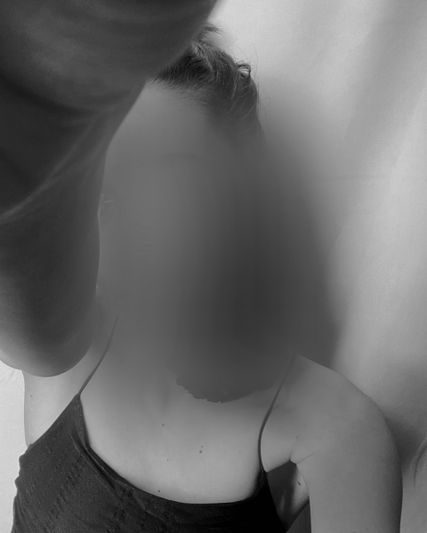 Une personne prend un selfie en noir et blanc, le visage flou. Elle porte un haut sans manches.