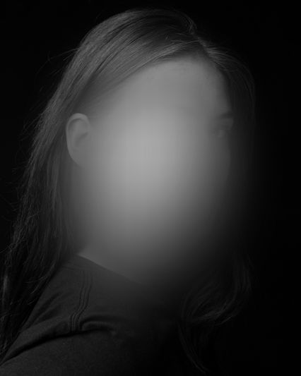 foto con desaturación de colores, mostrando a una mujer sobre un fondo negro con el rostro desenfocado